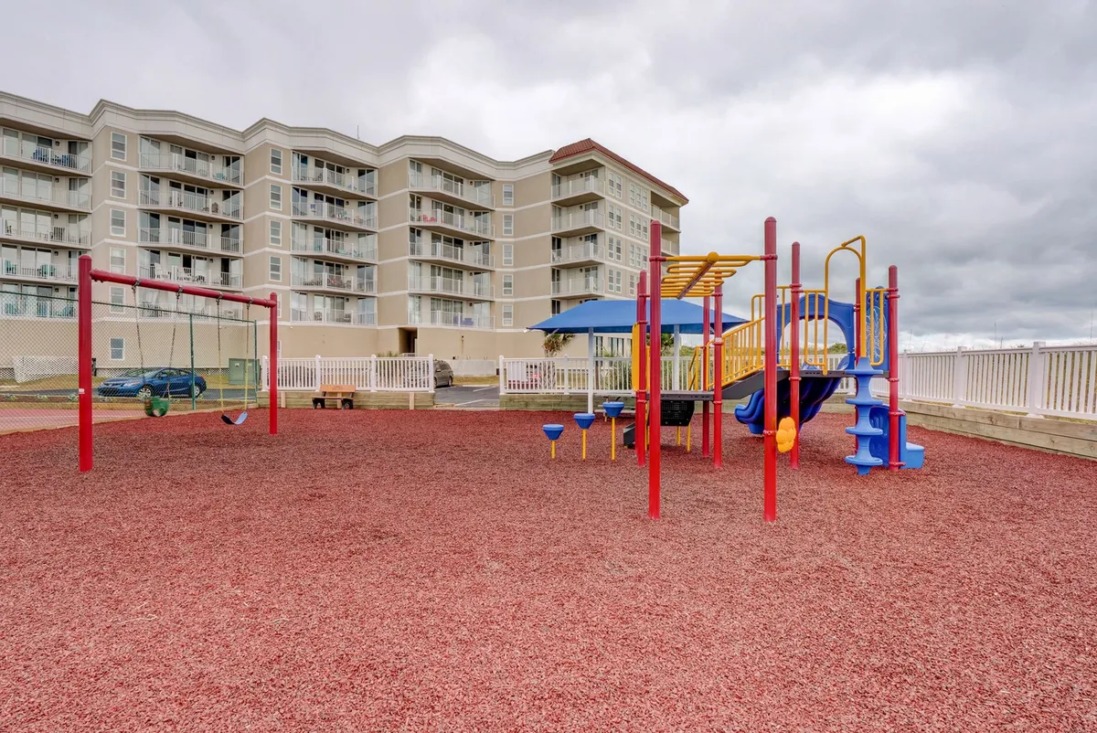 This exterior image features vibrant playground equipment and swings adjacent to the surrounding building. The area is lively and well-maintained, perfect for families with children seeking outdoor fun and play.