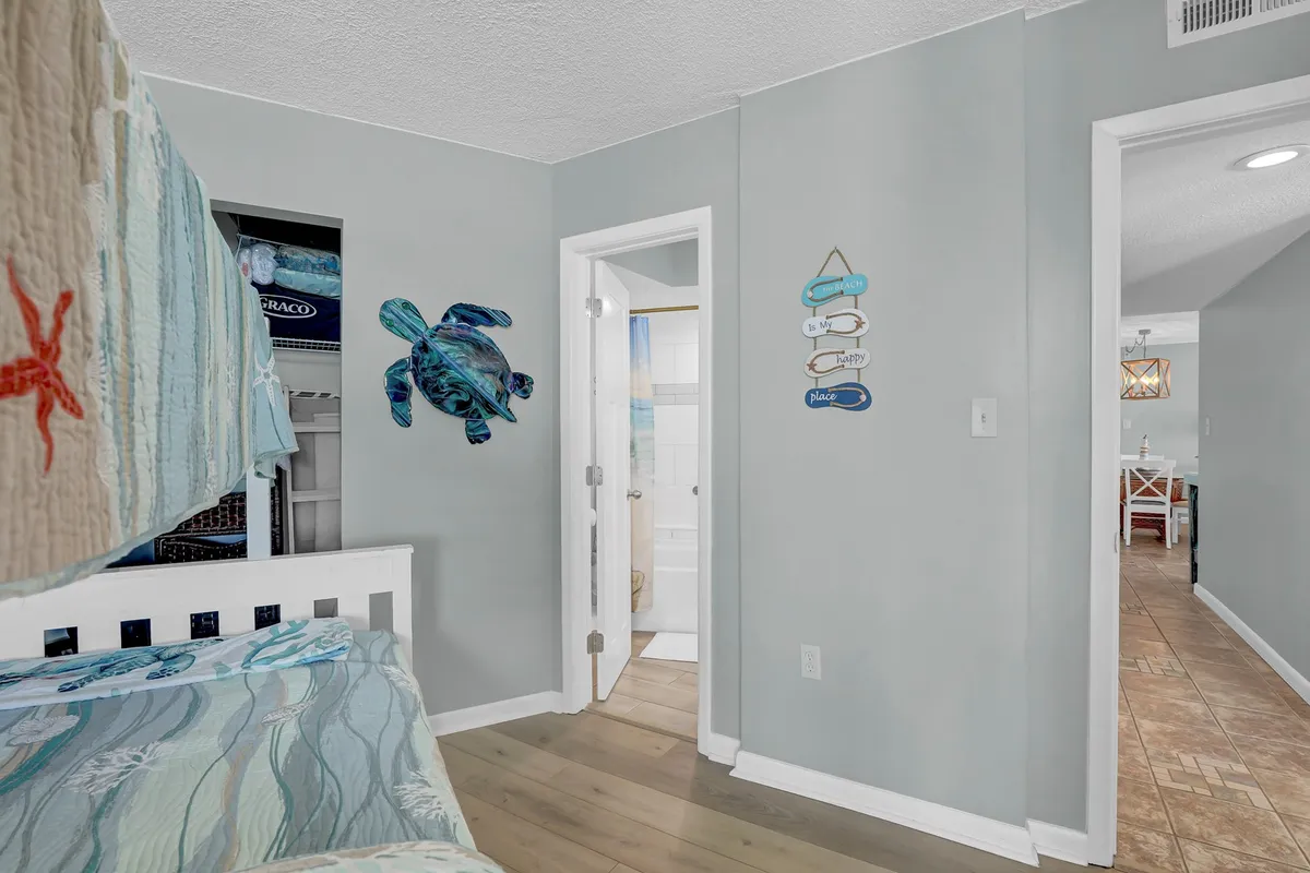 A playful bunk bedroom with an ocean-themed twin-over-full bunk bed, turtle wall art, and decorative wall signs. The mood is relaxed, with visible areas ideal for reading, playing games, and family bonding.
