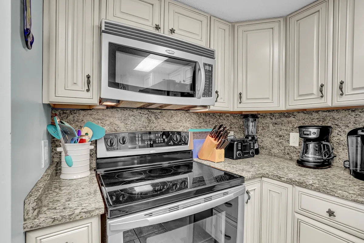 A contemporary kitchen with stainless steel appliances, granite countertops, and a colorful utensil holder is featured. The layout offers plenty of space for preparing meals or entertaining, and the modern amenities reflect the section’s note on the newly renovated kitchen.
